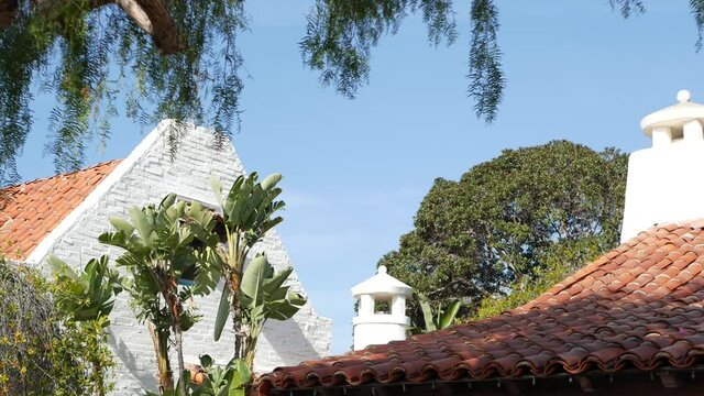 Mexican colonial style suburban, hispanic house exterior, green lush garden, San Diego, California USA. Mediterranean terracotta ceramic clay tile on roof. Rustic spanish tiled rooftop. Rural details.