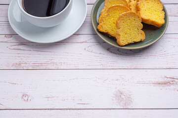 Crispy butter toast and a white coffee cup on wooden table with space for text