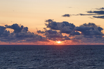 Sunset sky with sun at sea. Dramatic sunset clouds in the Baltic Sea view from the ferry. Horizontal orientation