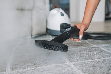 Woman cleaning carpet with a steam cleaner