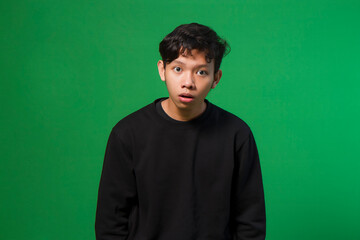 Obraz na płótnie Canvas asian young man with blank shocked expression. isolated on green background