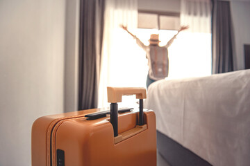 Close-up luggage and blurred happy tourist woman background in hotel after check-in. Conceptual of...