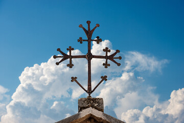 Obraz premium Medieval Christian cross in wrought iron on a blue sky with clouds. Verona, UNESCO world heritage site, Veneto, Italy, Europe.