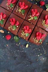 Chocolate mousse brownies with raspberry on dark background. Top view with copy space.