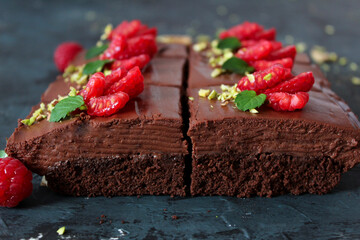 Chocolate mousse brownies with raspberry on dark background. Top view with copy space.