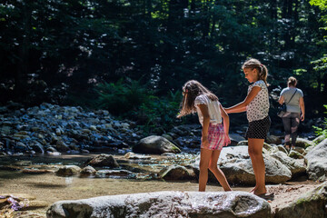 Fototapeta na wymiar Happy children have fun by mountain creek at summer forest. Natural day light. Adventure