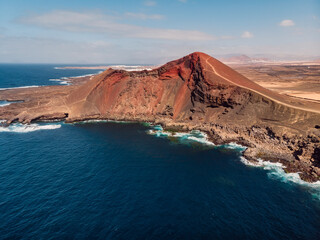 Fototapeta na wymiar Old volcano with red rock and Atlantic ocean near La Santa, Lanzarote. Aerial view