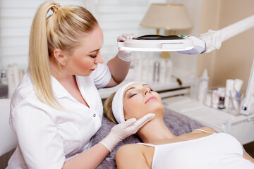beauty and plastic surgery concept - cosmetologist, beautician or doctor with young woman patient