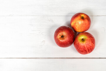 3 ripe red apples on white wooden background