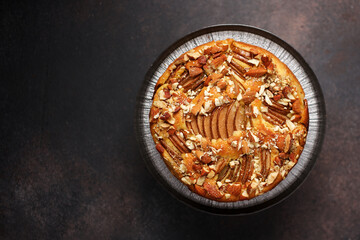 Pear pie with almonds on brown autumn background. Seasonal homemade cake