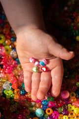 Colored beads in child's palms. A very colorful background of sparkling beads