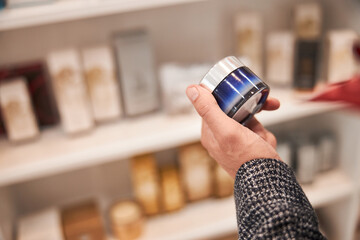 Hand of a person holding a product of cosmetics in a jar