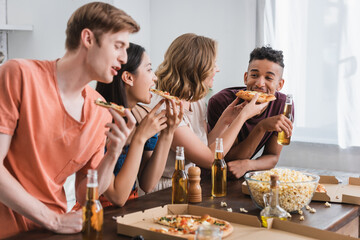 selective focus of joyful multiethnic friends eating pizza during party