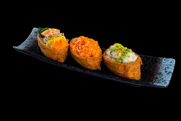 Inari sushi - sushi rice wrapped in dried tofu with Salmon and shrimp over black background Menu. Japanese kitchen