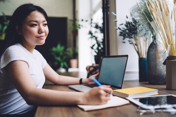 Content ethnic woman working on project on laptop at home