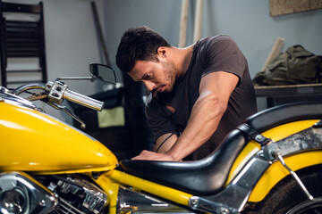 Fototapeta na wymiar A young mechanic tuning a motorcycle in an auto repair shop. Hobbies and work activity