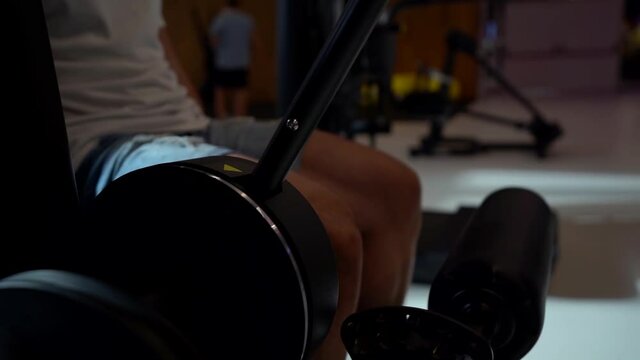 muscular man in the gym performs the leg extension exercise in the simulator to develop the muscles of the thigh