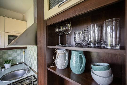 Tableware, mugs and glass utensils on the kitchen shelf