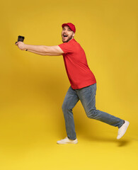 Delivery man in red cap blank t-shirt uniform isolated on yellow background. Guy employee hold takeaway cup of coffee