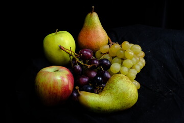 Fototapeta na wymiar Frutta con mele uva pere su sfondo nero