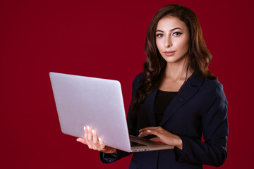 Beautiful young business woman with laptop on red background