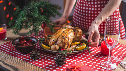Hands are holding a dish of baked chicken. Traditional Christmas dish for a festive dinner in a rustic style