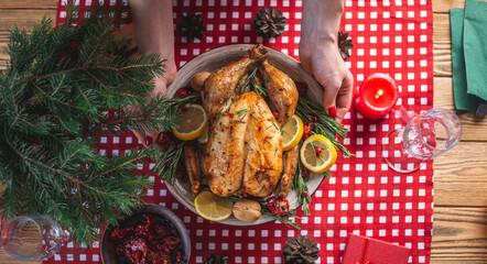 Baked chicken with rosemary and berries on a wooden table. Traditional Christmas dish for a festive dinner. Top view