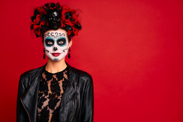 Young creepy lady calavera. wears artistic make-up for the feast of all the dead. dressed in a black leather jacket with a wreath of flowers on her head.Symbol of the Day of the Dead isolated in red.