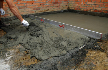 worker screeding indoor cement floor with screed
