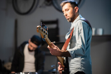 Fototapeta na wymiar a young pretty guitarist plays guitar in a garage at a band rehearsal