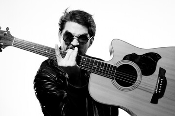 A man holds a guitar in his hands music emotions black leather jacket dark glasses studio light background