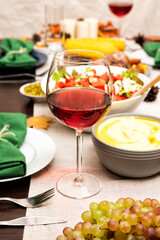 Glass of red wine on festive autumn holiday table setting with boiled pork, corn, mashed potatoes and candles. Thanksgiving family dinner.