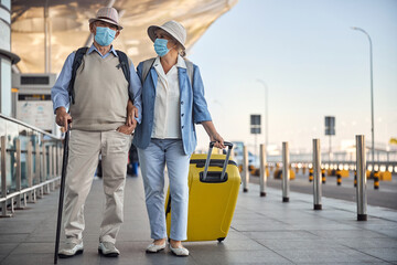 Fototapeta na wymiar Elderly married couple in face masks at the airport