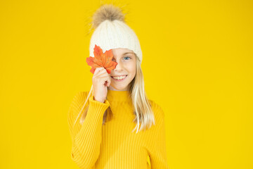 Smiling little girl playing with leaves and looking at camera. Autumn celebrate kids Clothing. Cute little child girl are getting ready for autumn sale. Close-up portrait