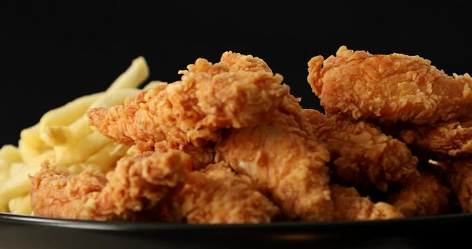 Tasty french fries and crispy chicken nuggets with mustard and ketchup isolated on black