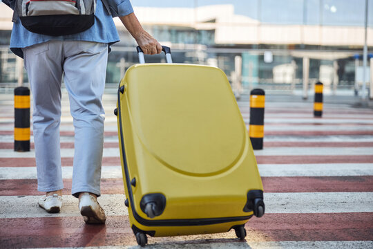 Aged lady with luggage walking across the street