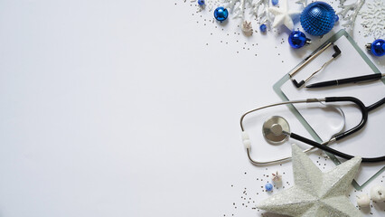 Christmas medical banner christmas decor white stars,blue balls, snowflakes, stethoscope and tablet on white background top view. Copyspace. Medicine new year flatly. Doctor writes down the text