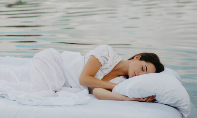 Woman sleeps on a mattress floating in the water.
