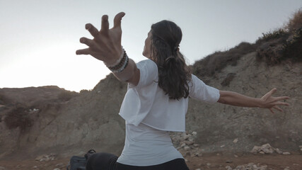 Young woman with outstretched hands doing yoga in early morning on the beach. High quality photo