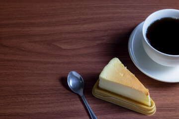 Cheesecake with hot coffee on a dark wooden table and copy space