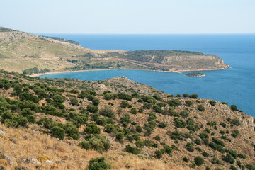 Rocky seashore covered with bushes and grass. Peninsula and rocks, Greece.