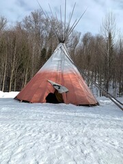Red and white teepee tipi in a winter snow pine forest in Laurentides, Quebec, Canada.