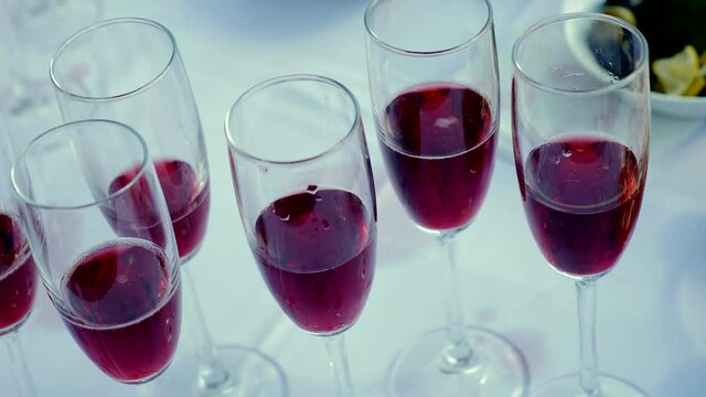 Close-up of glasses with raspberry champagne wine. The glasses are on a white tablecloth