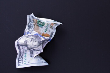 Crumpled one hundred dollar bill on a black background. The concept of the fall of the dollar as a result of the coronovirus pandemic