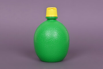 Concentrate lemon juice in a green bottle on a gray background.