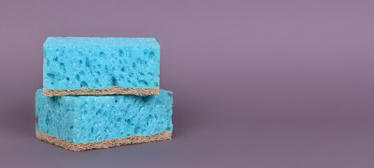 A porous blue washcloth for cleaning the apartment and washing dishes on a gray background.