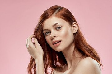 Pretty woman with long beautiful hair grooming hairstyle glamor naked shoulders pink background