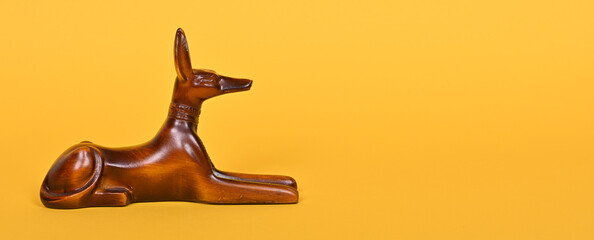 The ancient God of Egypt Anubis, a statue of a dog on a yellow background.