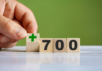 hand turn wooden block with plus sign and set text "+700"