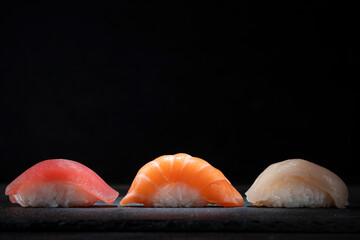 Japanese sushi set with salmon, tuna and perch on a black stone background © Andrey